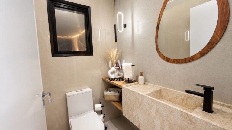 Lavabo com cuba esculpida em mármore e espelho redondo
